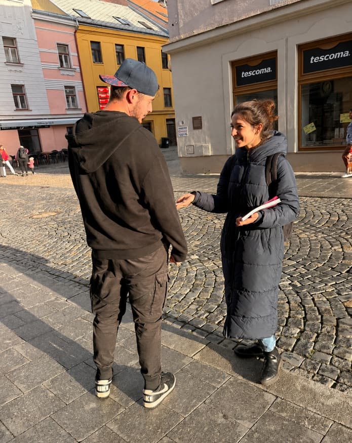 Promotérka předává leták kolemjdoucímu v centru města
